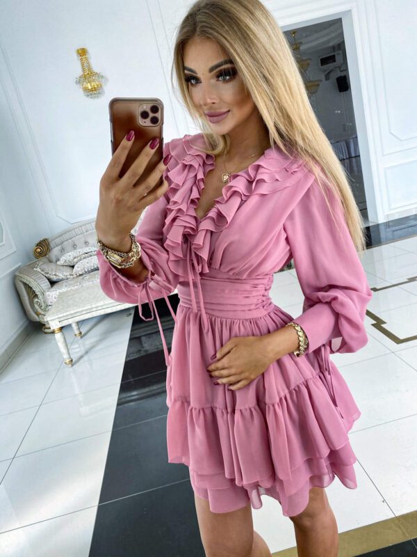 Side view of a model wearing a Sophia Dust Pink Mini Party Dress, highlighting its layered ruffle skirt and flattering fit.